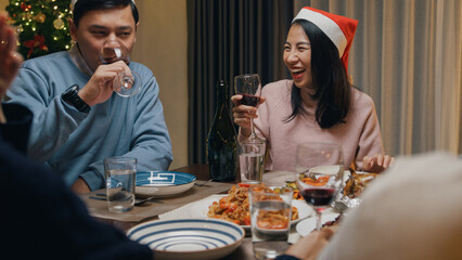 Group of Asia colleague friends gathering New year holidays party together. Happy man host toast glass of wine with guest start eat christmas dinner at home in evening, celebration and people concept.