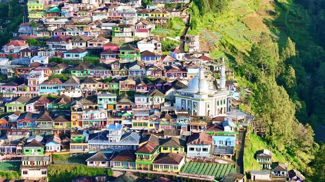 Aerial view of a colorful mountain village in Mount Sumbing, Central Java, Indonesia, with vibrant houses and a mosque surrounded by lush green hills. Nepal Van Java.
