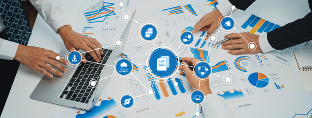 A team engages in a collaborative business management session, analyzing data and presenting strategies using charts and graphs in a modern office setting. Amity