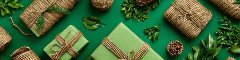 Wrapped gifts arranged on green background, adorned with greenery and twine, create a visually appealing display