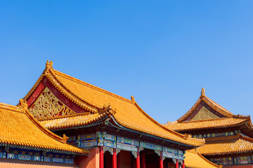 Naklejka premium Sunlit golden roof with ornate ridge figures and vivid painted beams provides clear view of traditional Chinese imperial architecture in Forbidden City, Beijing, China