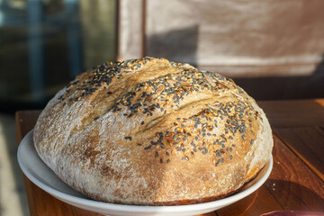 Artisan rustic sesame seed bread loaf on wooden table in warm natural light, showing crust texture and homemade bakery style ideal for food photography, organic cooking, and culinary visuals