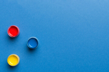 jars with gouache of different colors on Colored background. hobby painting. Top view with empty space. workplace for creativity. home teaching concept drawing