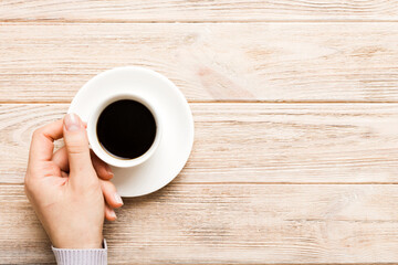 Minimalistic style woman hand holding a cup of coffee on Colored background. Flat lay, top view espresso cup. Empty place for text, copy space. Coffee addiction. Top view, flat lay