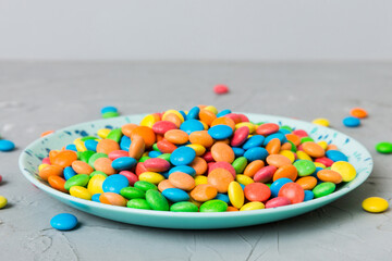 Multicolored candies in a bowl on a colored background. birthday and holiday concept. Top view with copy space