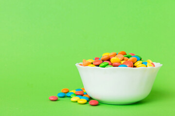 Multicolored candies in a bowl on a colored background. birthday and holiday concept. Top view with copy space