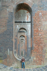 View of a young man wearing a black T-shirt and jeans standing on the structure under the bridge of Ouse Valley Viaduct or Balcombe Viaduct, has been described as &acirc;the most elegant viaduct in Britai