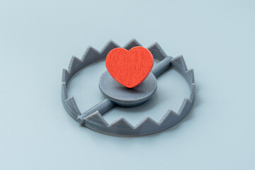 A red heart is placed inside a bear trap. Betrayal, heartbreak, relationship risk, love trap, toxic...