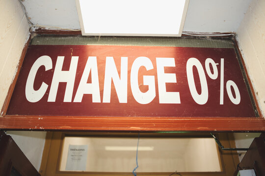 Red sign with white text change 0 percent hangs above a commercial counter in an old, run down office, representing concepts of stagnation, resistance, and financial immobility