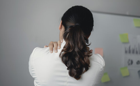 Woman having shoulder pain pain during work long time. stretching to relax and relax while working hard at the office