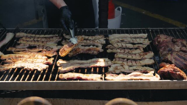 Close-up of grilling meat on an outdoor barbecue grill in summer. Preparing beef and chicken over smoky charcoal. Picnic time with an outdoor grill party.