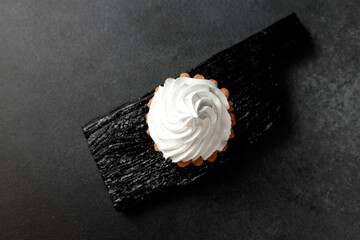 A sand basket with protein cream stands on a black wooden board on a gray background