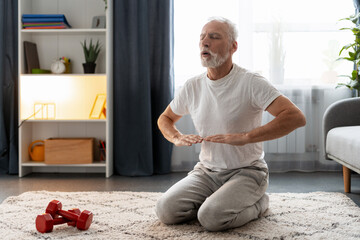 Senior man practicing breathing exercise on floor at home, embracing wellness and mindfulness