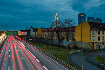 Light trails on motorway in Gothenburg during evening hours with buildings and signs in view