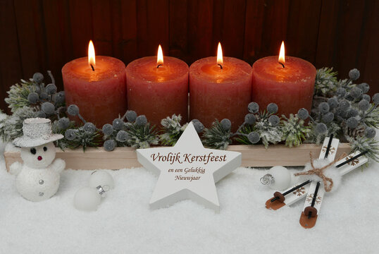 Kerstkaart: Kerstgroeten in het Nederlands. Wintertafereel met bruine kaarsen, kerstballen en dennentakken in de sneeuw. Vrolijk kerstfeest en een gelukkig nieuwjaar.