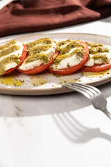 Italian caprese salad with tomatoes and mozarella. Pesto sauce and olive oil.