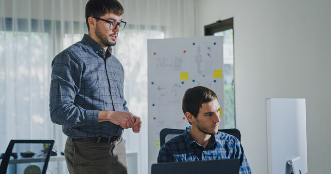 Team adult male engineer collaborate on robotic hand project using AI code solutions machine learning at tech workspace. Artificial intelligence interface, collaboration support prototype development.