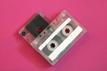 Two vintage cassette tapes forming heart shape on pink background