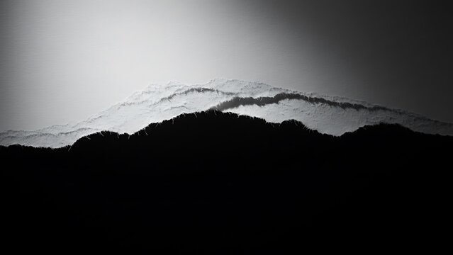 Abstract black and white mountain silhouette against bright sky - Powered by Adobe