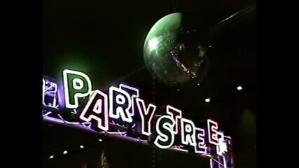 Colorful neon Party Street sign under large hanging disco ball in VHS-style nightclub setting - Powered by Adobe