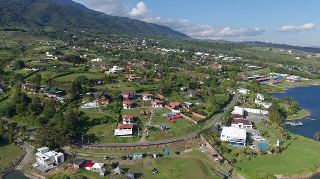 Drone video capturing the lush, expansive landscape of Lago Calima. Green hills, vibrant foliage, and serene waters create a breathtaking view under clear blue skies.