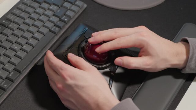 Man using Trackball as a mouse and typing on keyboard