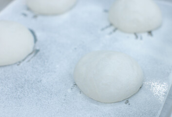 Smooth ball of fresh dough rests on floured stainless steel table in clean food preparation area, Factory production line baking preparation professional kitchen workflow industrial technology concept