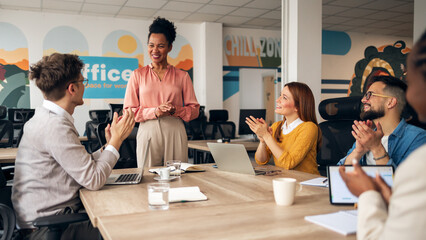Team Applauding a Colleague During a Business Presentation in a Modern Office
