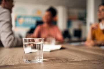 Close-Up Glass of Water With People Discussing in the Background