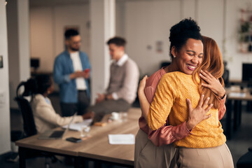 Two Women Hugging in a Collaborative Office Environment