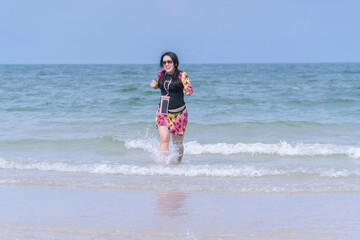 Asian woman playing happily in the sea at the beach