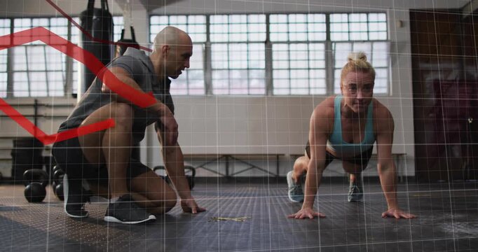 Coach cueing trainee on mat, pushing up while red graph rising over scene tracking reps