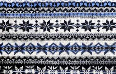 Wool sweater texture with decorative ornament of white, blue, and gray color. Natural wool material with knitted ornament. Horizontal or vertical Christmas background with knitted fabric texture