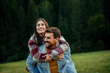 Young couple enjoying piggyback ride in nature
