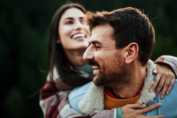 Happy couple enjoying outdoor piggyback ride on a trail