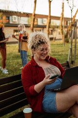 Obraz premium Plus size student using laptop and phone on campus
