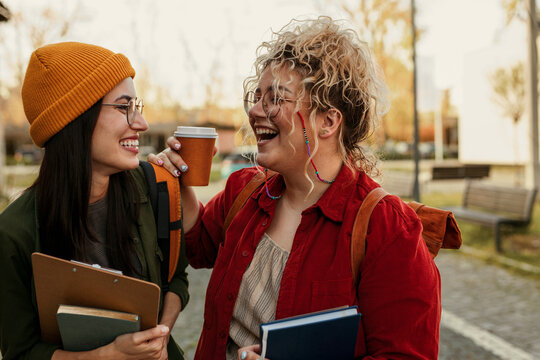 Fototapeta Female students laughing, enjoying coffee on campus