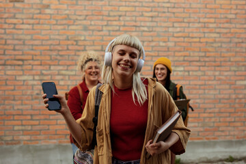 Young woman enjoying music with friends standing outdoors