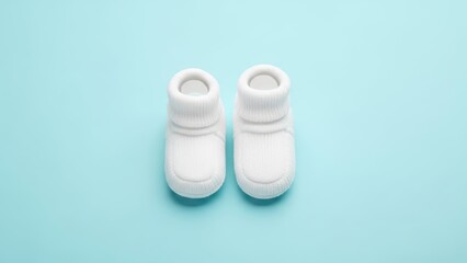 Adorable white baby booties on light blue background