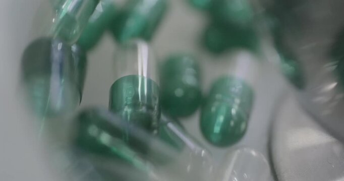 Empty transparent medicine capsules move along a sorting line. Close-up shot, real time speed, artificial indoors light.