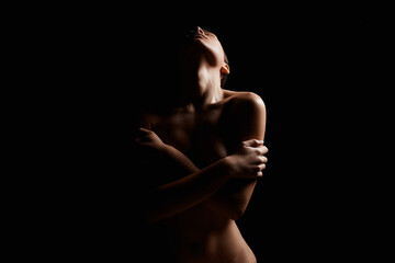 Naklejka premium Nude Woman silhouette under light in the dark