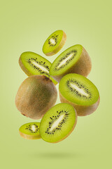 Juicy kiwi slices with fuzzy brown skin, vibrant green flesh fly as swirl art composition on green background. Ideal for creating healthy desserts menu, branding of summer antioxidant organic food.