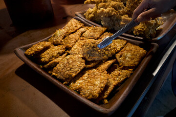 Close up of Tempe Garit Goreng (fried soybean cake) on a clay pan. Indonesian traditional food