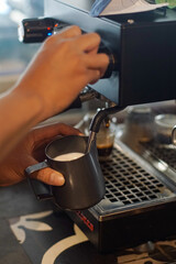 Close-up of a barista steaming milk using an espresso machine in a coffee shop. Authentic café workflow, warm lighting, and professional barista preparation perfect for food, beverage, and hospitality