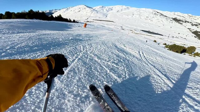 First person view skiing downhill on sunny ski resort slope