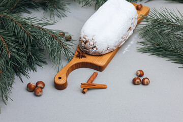 Christmas stolen in powdered sugar on a light background with pine branches and tangerines. Traditional Christmas delicacies. Top view