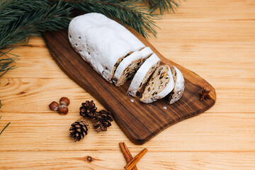 Christmas stolen in powdered sugar on a light background with pine branches and tangerines. Traditional Christmas delicacies. Top view