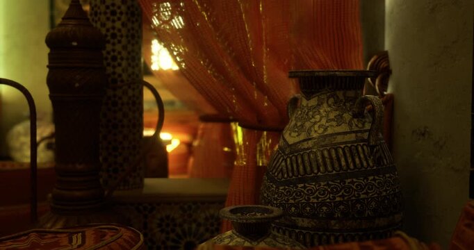 Decorative pottery is displayed alongside richly patterned textiles in a warm room filled with soft light. The vibrant colors create an inviting and intimate atmosphere.