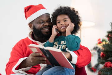 African American family reading book together at home. African American father and baby reading book on Christmas day