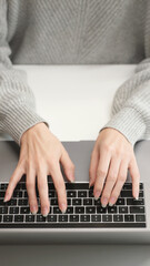 Top view of woman's hands typing on laptop keyboard, close-up. Work, AI prompt, research, social networks, and remote education in a modern workspace.